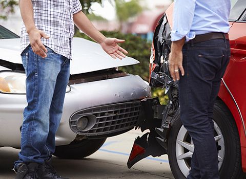 Zwei Männer diskutieren vor beschädigten Autos